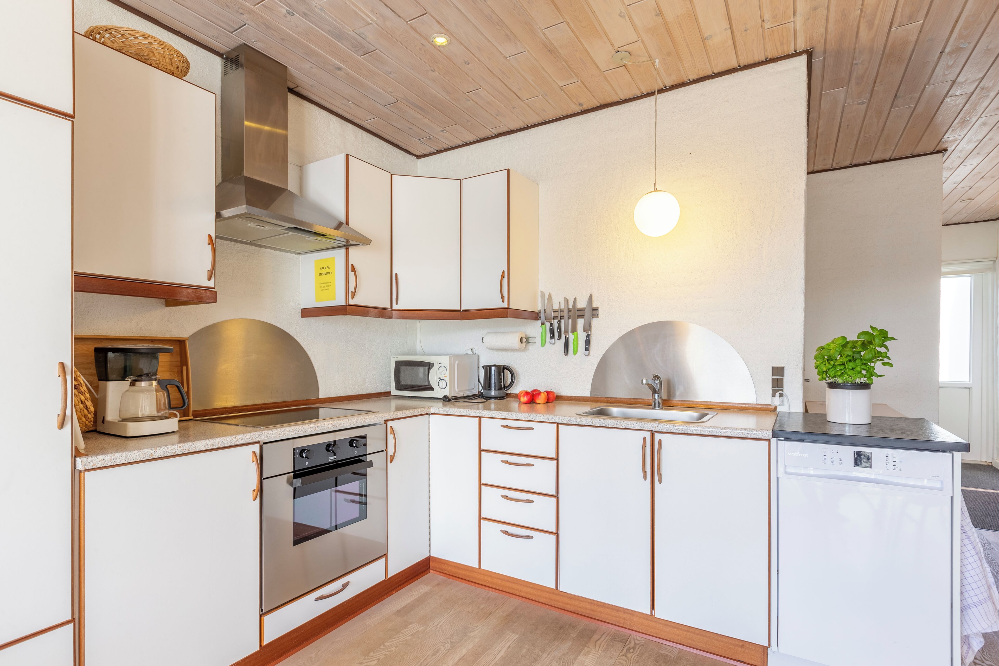 Una cocina moderna con armarios blancos, electrodomésticos de acero inoxidable y suelo de madera.