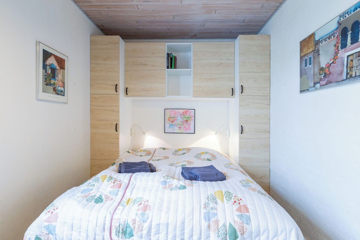 Ein Schlafzimmer mit einem Bett, einem Kleiderschrank und einem Regal über dem Bett.