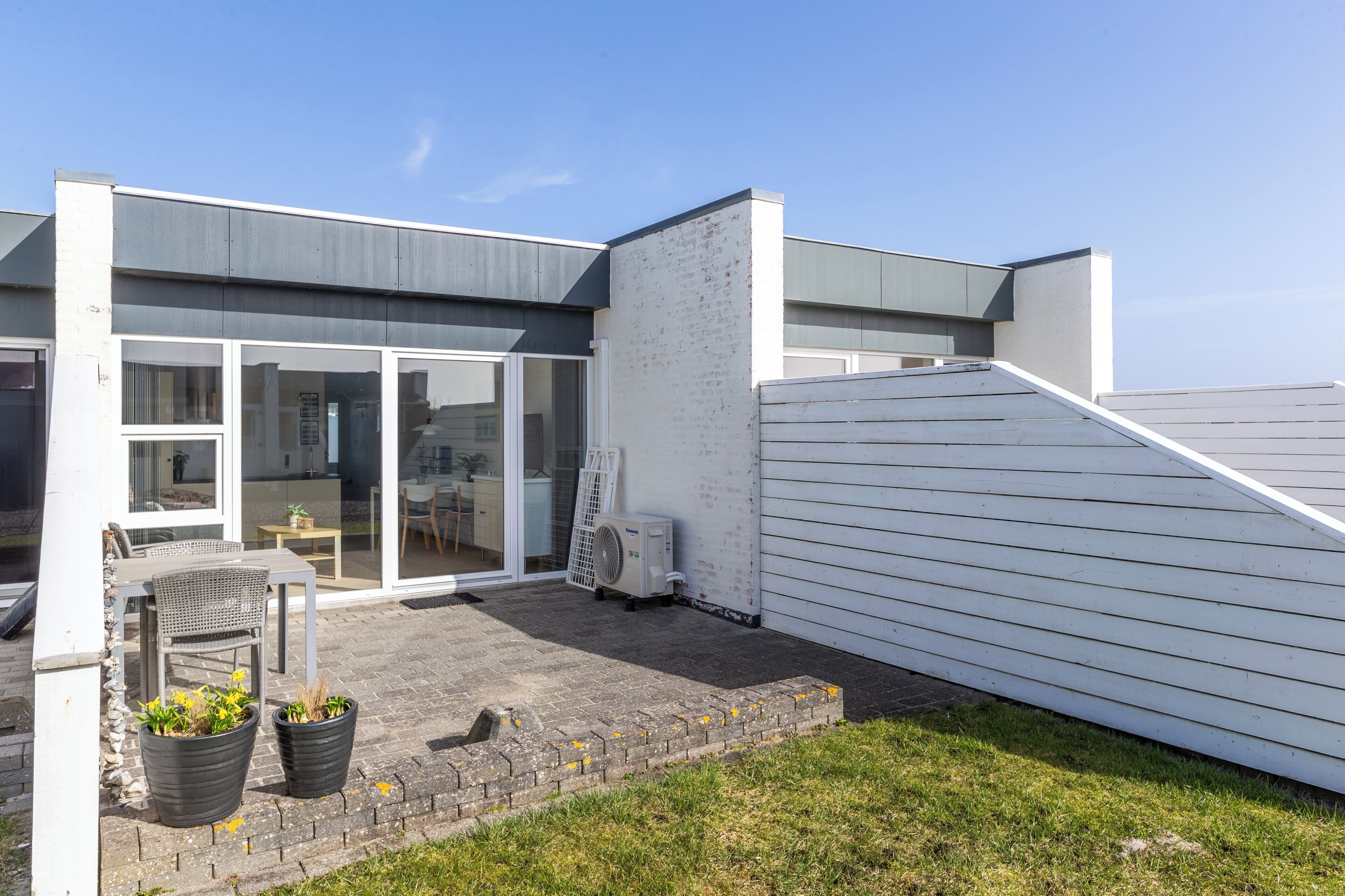 A modern house with a patio, a dining area, and a large window.