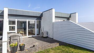 A modern house with a patio, a dining area, and a large window.