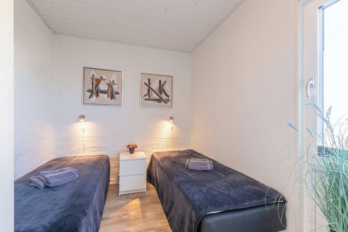 Ein Zimmer mit zwei Betten, einem kleinen weißen Tisch und zwei Wandleuchten.