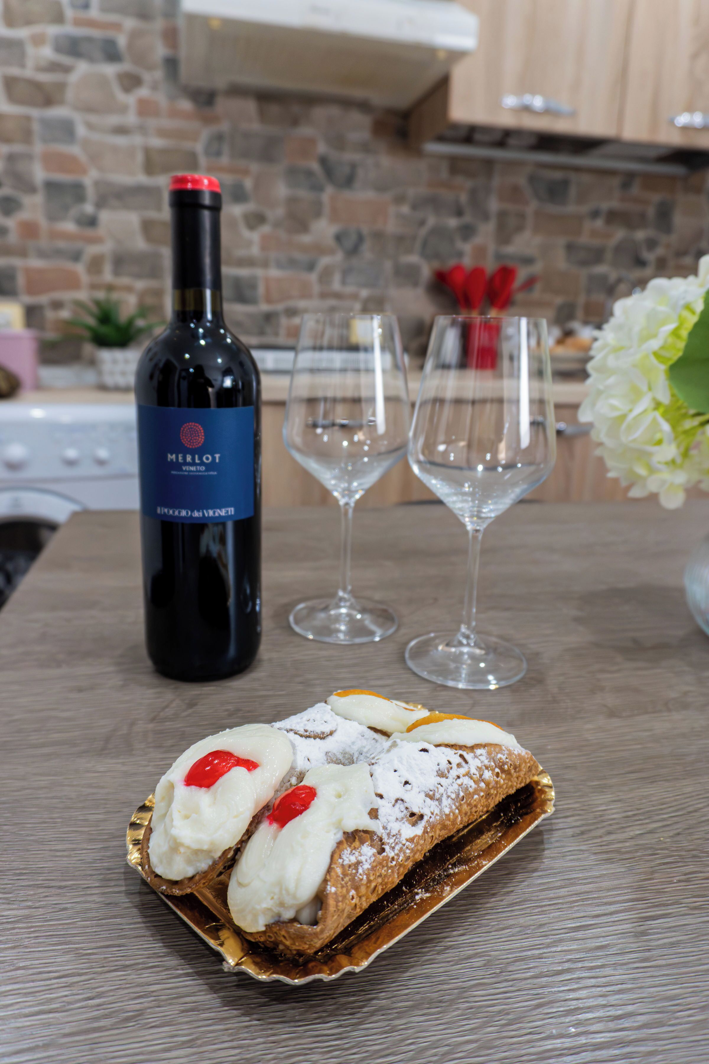 Une bouteille de vin rouge de Merlot, deux verres à vin vides et un dessert sur une table.