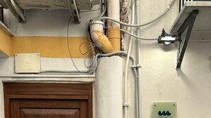 Une porte en bois avec une poignée en métal, un mur de pierre et une enseigne indiquant « MESCHITA SETTE » avec un numéro de téléphone.