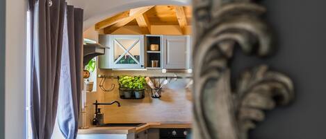 A modern kitchen with wooden beams, a built-in oven, and a window with curtains.