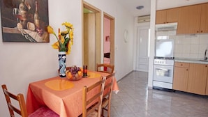 Un comedor con una mesa dispuesta para dos personas, un jarrón con flores y un cuadro en la pared.