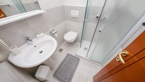 Ein modernes Badezimmer mit einem großen Waschbecken, einer Toilette und einer Duschkabine aus Glas.