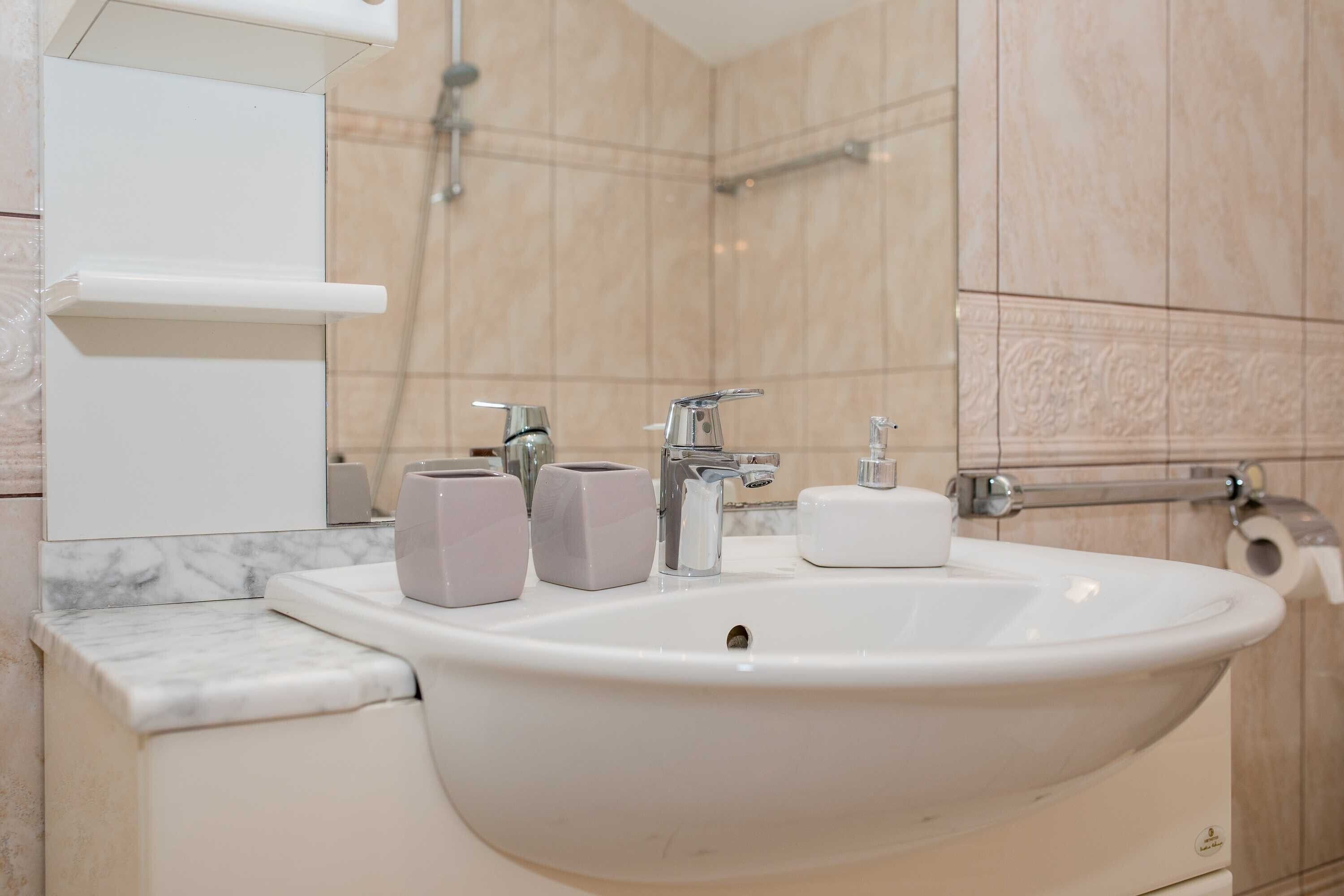 A bathroom with a large sink, two faucets, a mirror, and a towel rack.