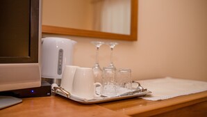 Una bandeja con una taza blanca, un vaso y un juego de vasos sobre una mesa de madera.