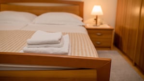 Una cama bien hecha con toallas dobladas, una lámpara de noche y muebles de madera.