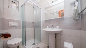 Une salle de bain moderne avec une douche à parois de verre, un lavabo sur colonne et des toilettes.