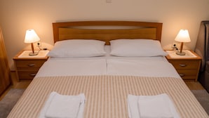 Un lit double avec deux oreillers blancs et deux tables de chevet avec des lampes.