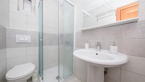 Une salle de bain moderne avec une douche à parois de verre, des toilettes et un lavabo avec un miroir au-dessus.