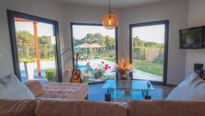 A modern living room with a glass coffee table, a pink sofa, and a guitar.
