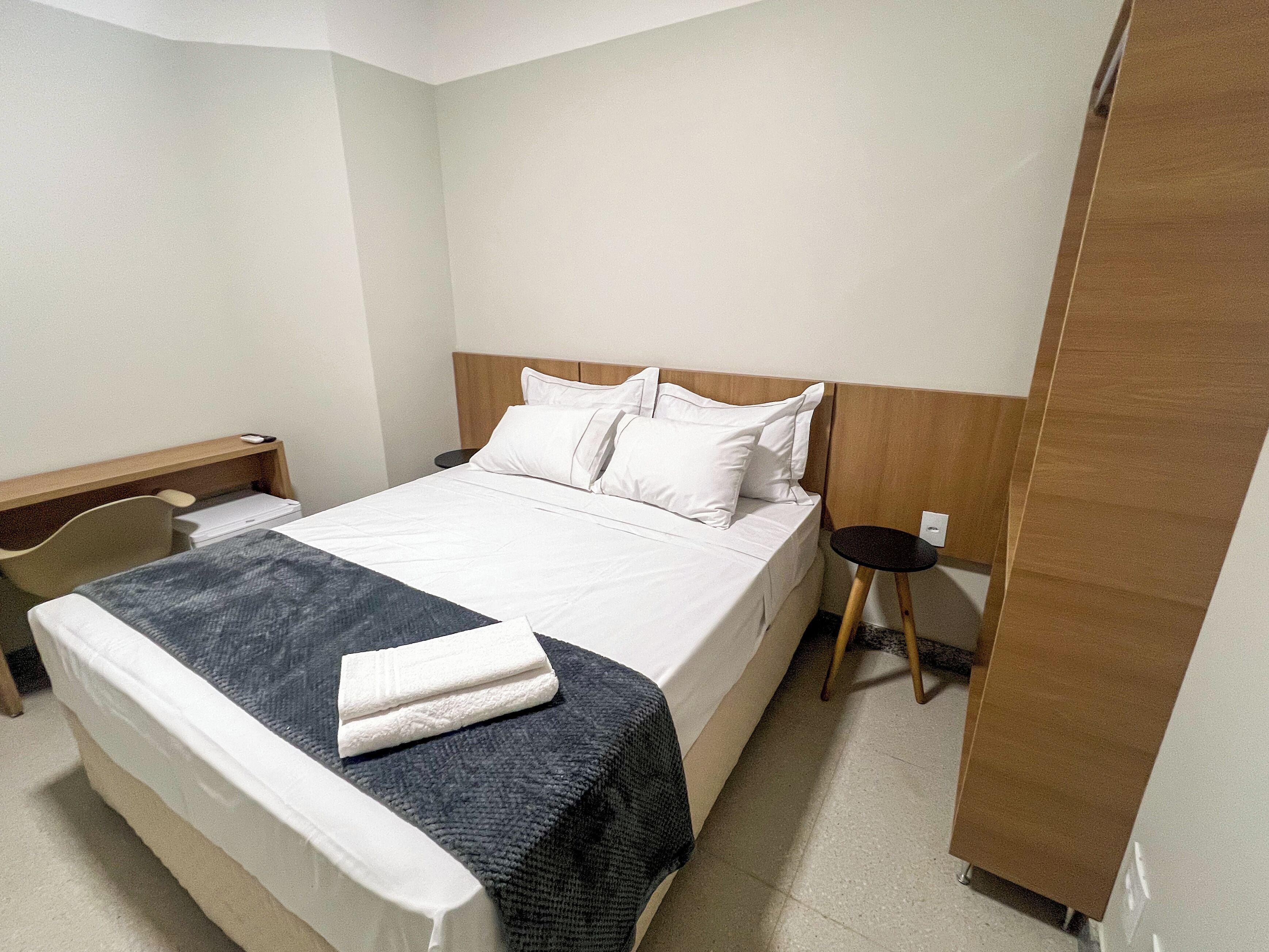 A hotel room with a bed, a desk, and a chair.