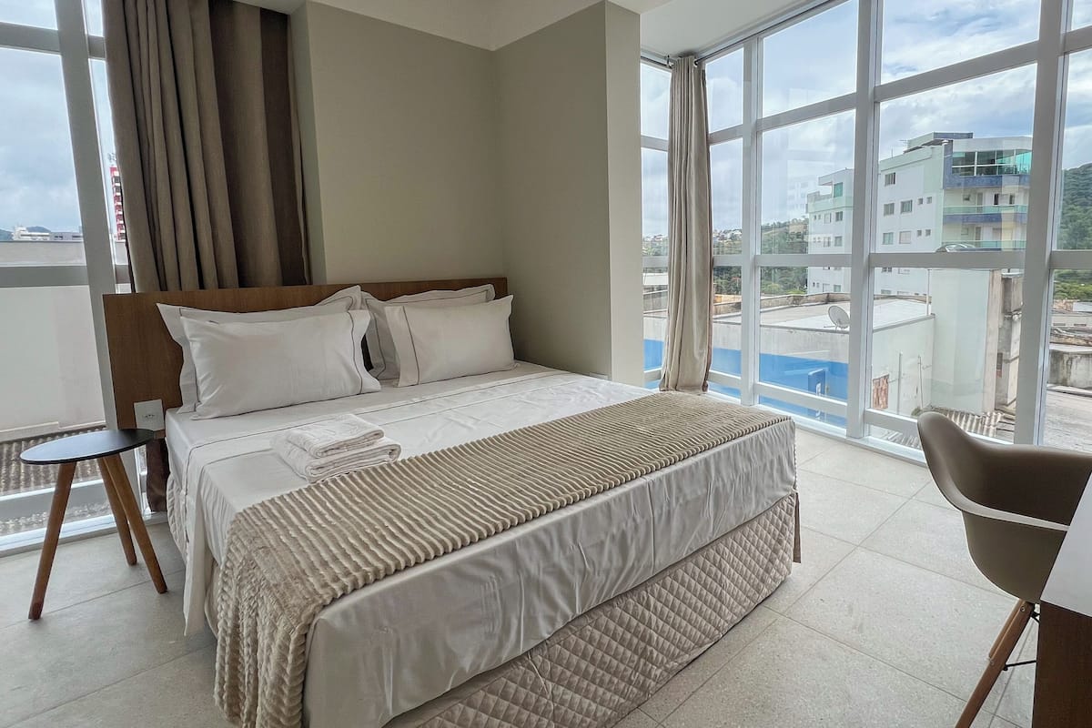 A hotel room with a large bed, a view of the city, and a balcony.