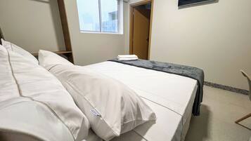 Una habitación de hotel con una cama, una ventana, un aire acondicionado y una puerta.