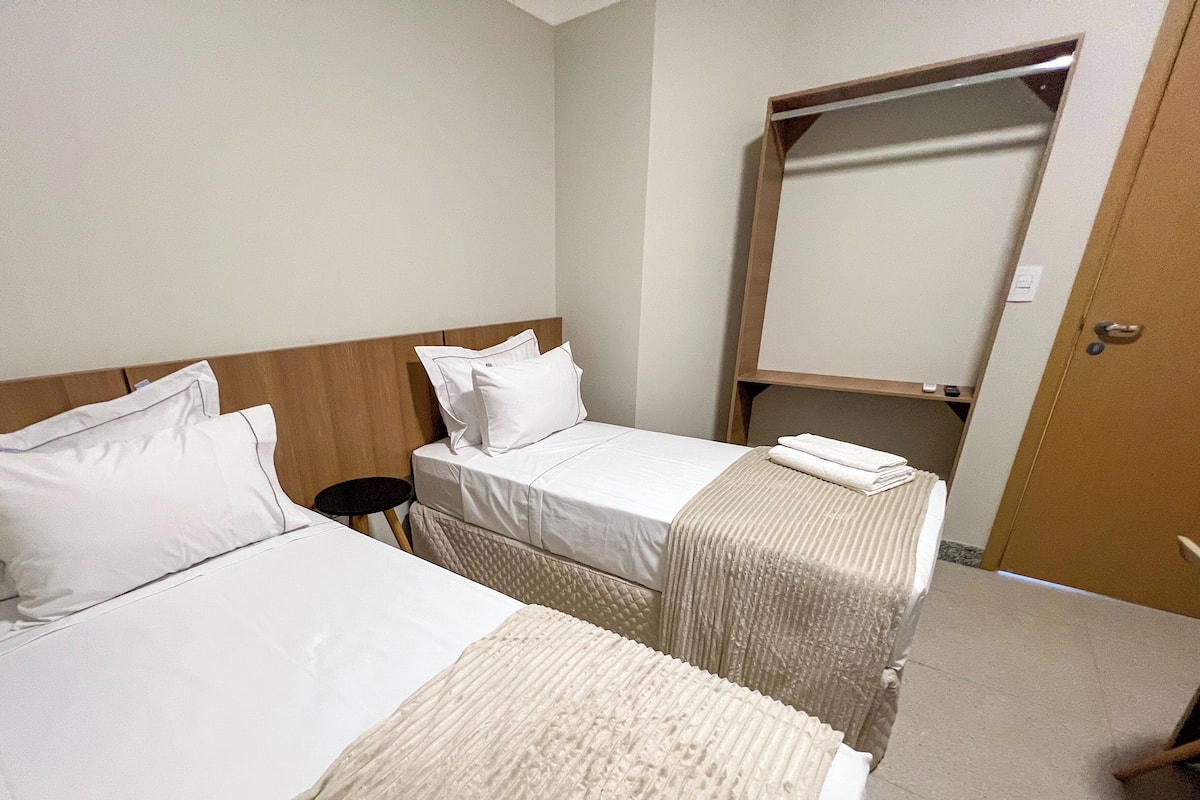 A hotel room with two beds, a small round table, a mirror, and a door.