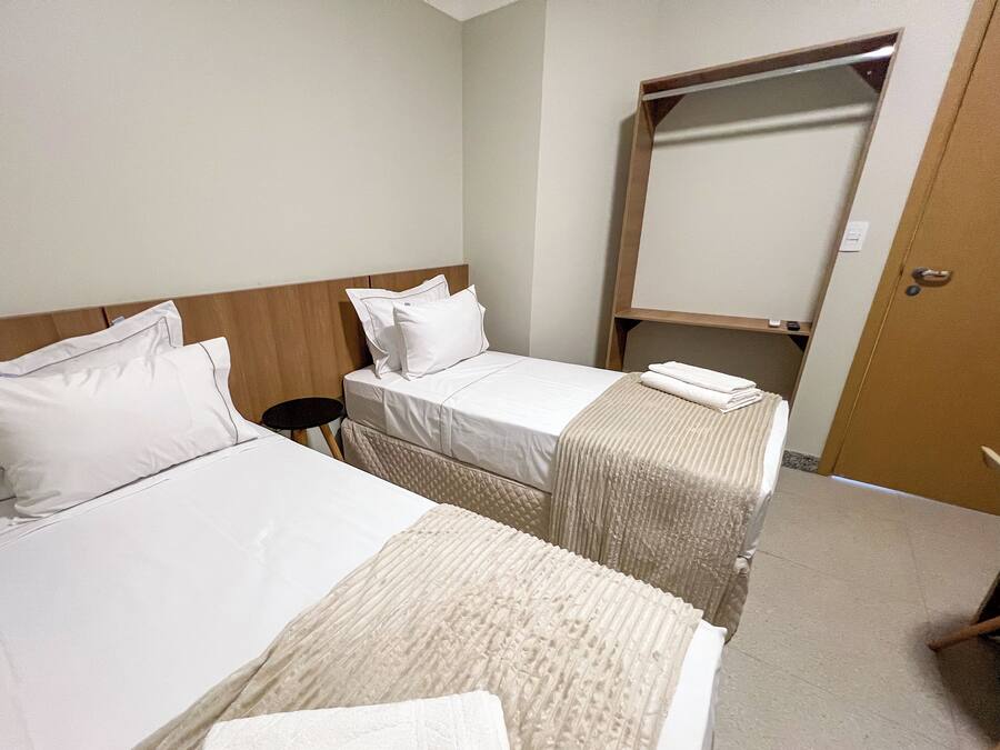 Une chambre d’hôtel avec deux lits, une petite table ronde, un miroir et une porte.