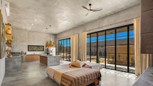 Ein modernes Schlafzimmer mit einem großen Bett, einer kleinen Küchenzeile und einem Balkon mit Blick.