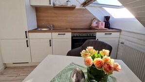 A compact kitchen with white cabinets, a wooden countertop, and a skylight above. - Vacation apartment "Still Hörn 1" in Greetsiel (approx. 30 sqm / 2 persons) (Krummhörn)