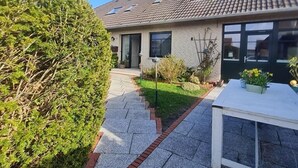 A residential building with a tiled roof, a paved pathway, and a neatly trimmed hedge. - Vacation apartment "Still Hörn 1" in Greetsiel (approx. 30 sqm / 2 persons) (Krummhörn)