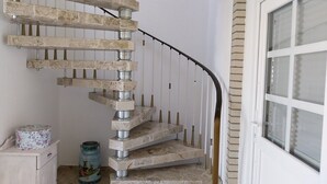 A spiral staircase with a white exterior and a black handrail, leading to a door with a window. - Vacation apartment "Still Hörn 1" in Greetsiel (approx. 30 sqm / 2 persons) (Krummhörn)