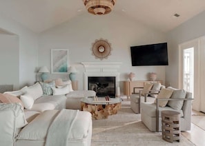 A living room with a fireplace, sofas, a coffee table, and a TV mounted on the wall.