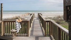 A wooden deck leading to a beach with a view of the ocean. - Oceanfront 7-bed home with grass backyard & grill (Folly Beach)