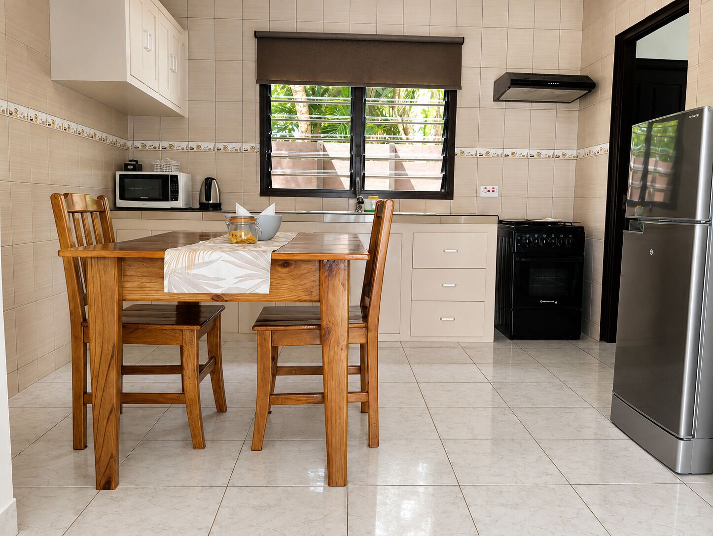 A kitchen with a dining table, chairs, a microwave, a stove, and a refrigerator.