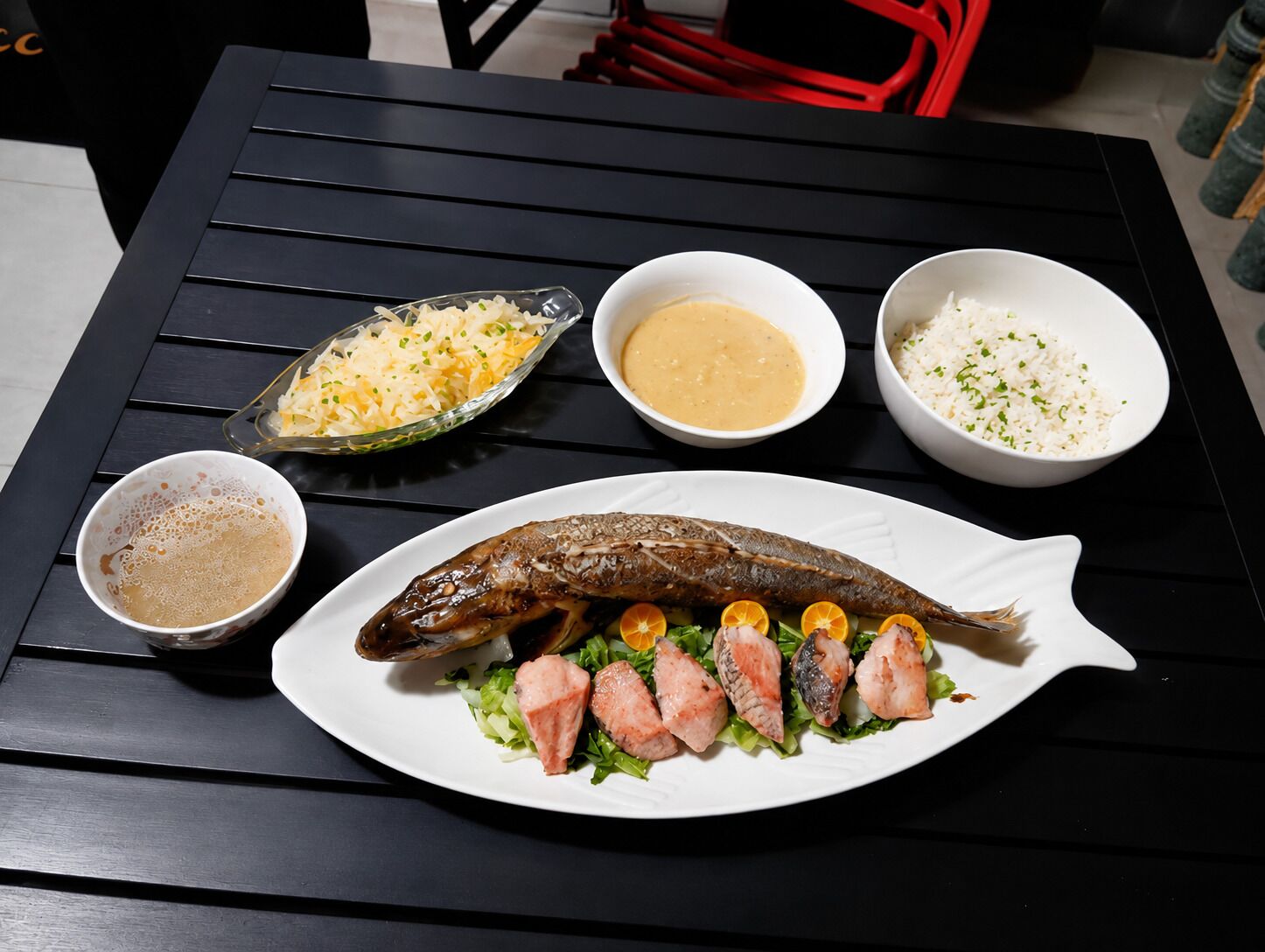 A table with a fish dish, side salad, and three bowls of different sauces.