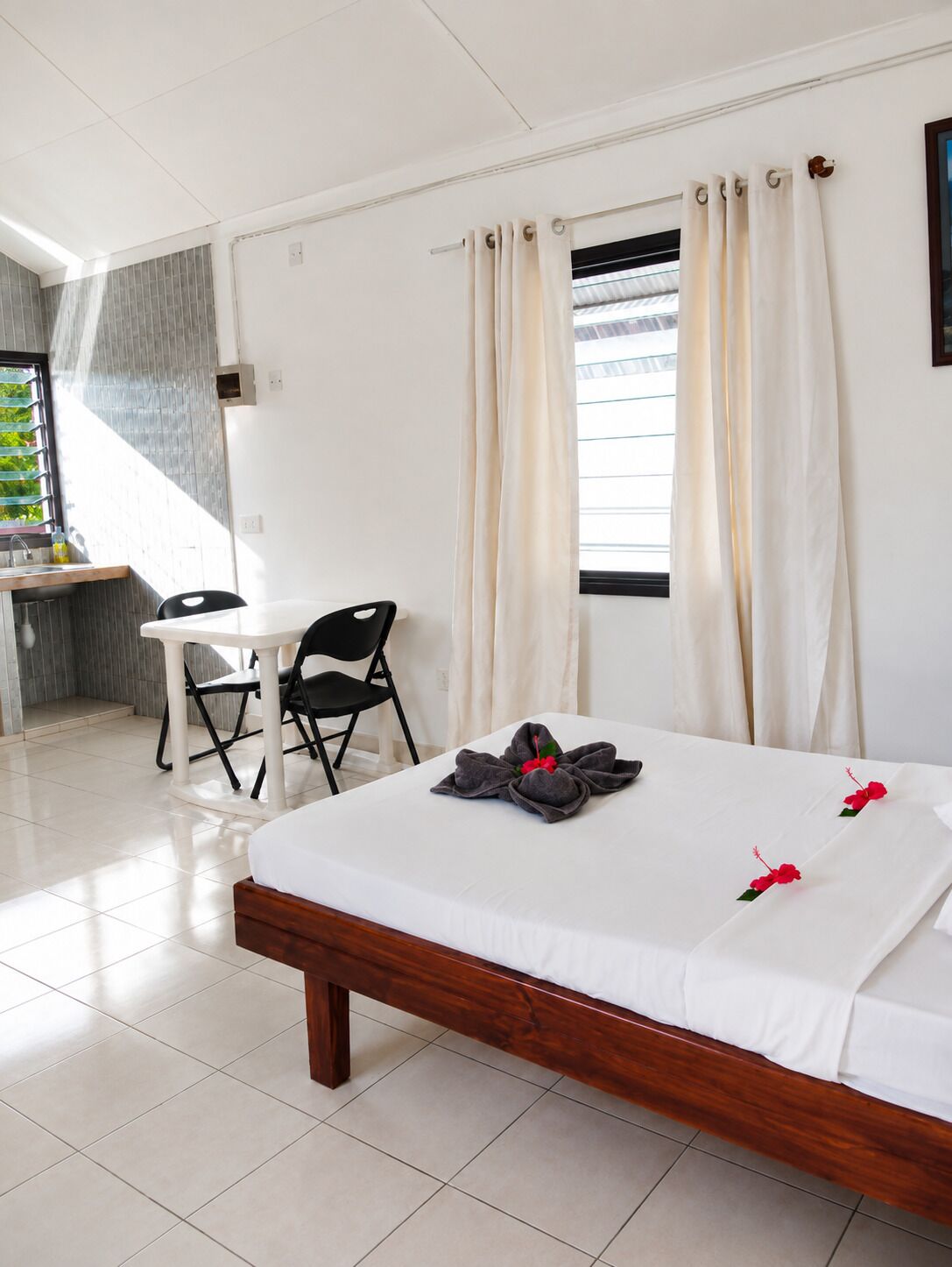 Una habitación de hotel con cama, escritorio y silla, y ventana con cortinas.