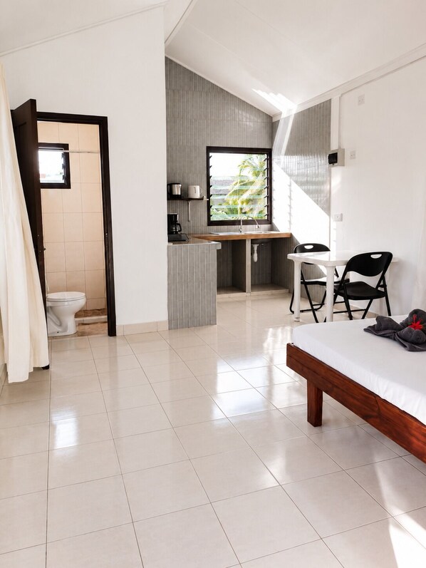 Een moderne slaapkamer met een bed, een bureau en een stoel. Er is een badkamer met toilet en douche.