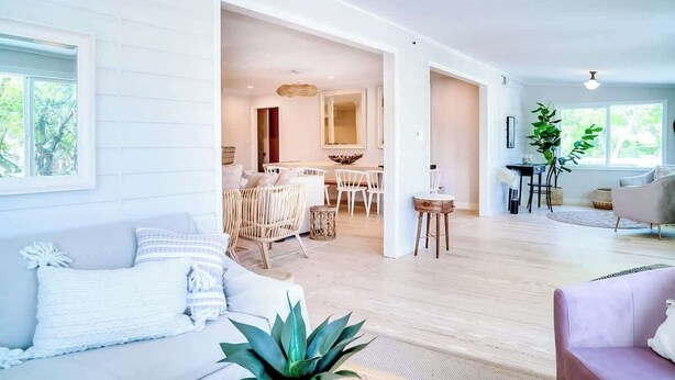 Un grand espace de vie comprenant un canapé, une table à manger avec des chaises, un coin cuisine et une grande fenêtre.