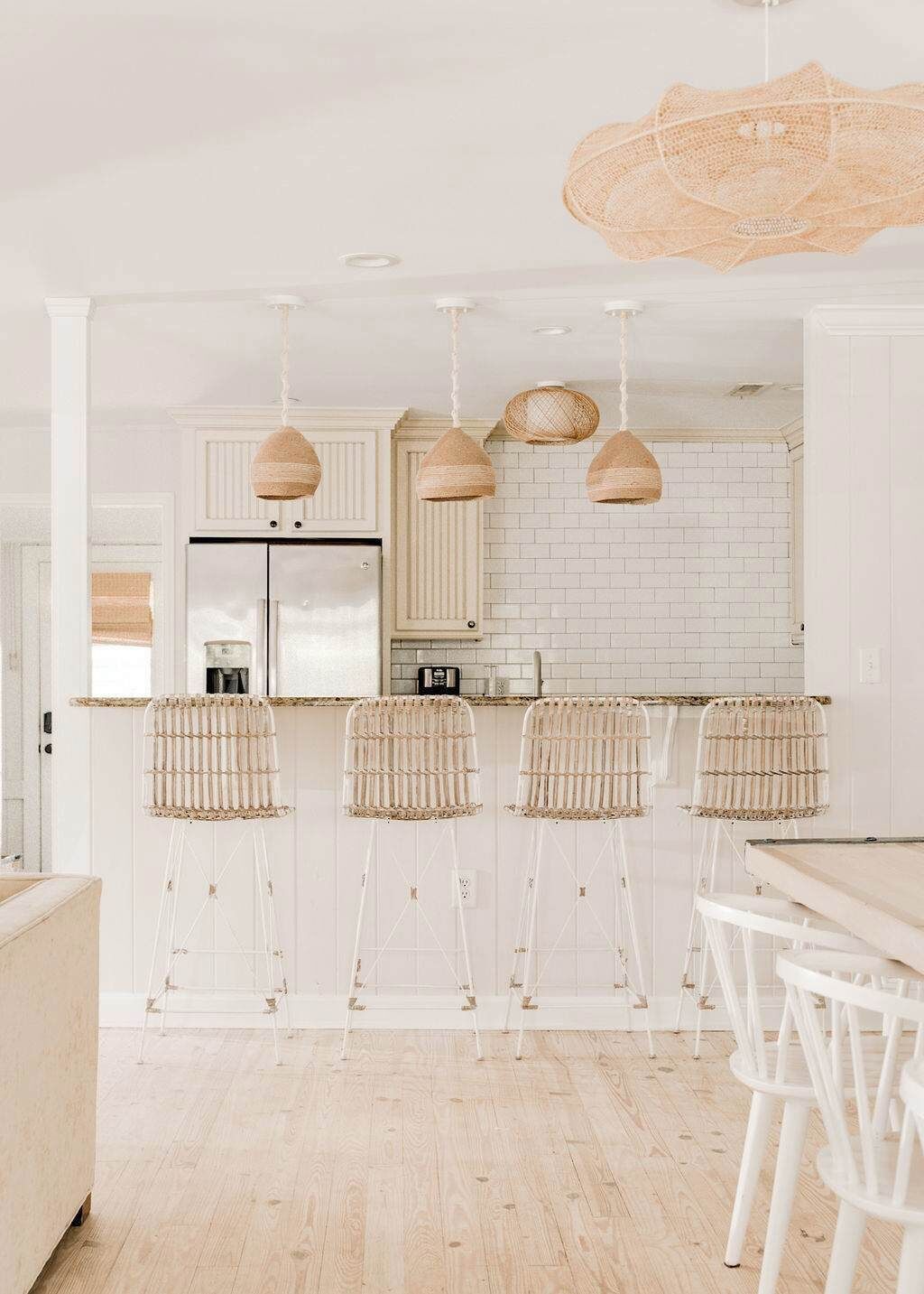 A kitchen with white cabinetry, a stainless steel refrigerator, and a white brick backsplash.