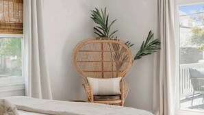 Ein Schlafzimmer mit einem Bett, einem Korbstuhl, einem Deckenventilator und Blick durch ein Fenster.