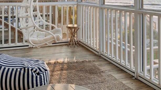 Ein geräumiger Balkon mit Hängesessel, einem kleinen runden Tisch und einem gestreiften Sitzsack.