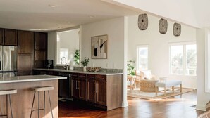 A spacious kitchen with a large island, wooden cabinets, and a view to a dining area.
