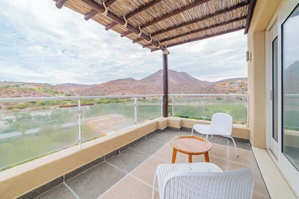 Un balcón con vistas a un paisaje montañoso, una mesa y dos sillas.