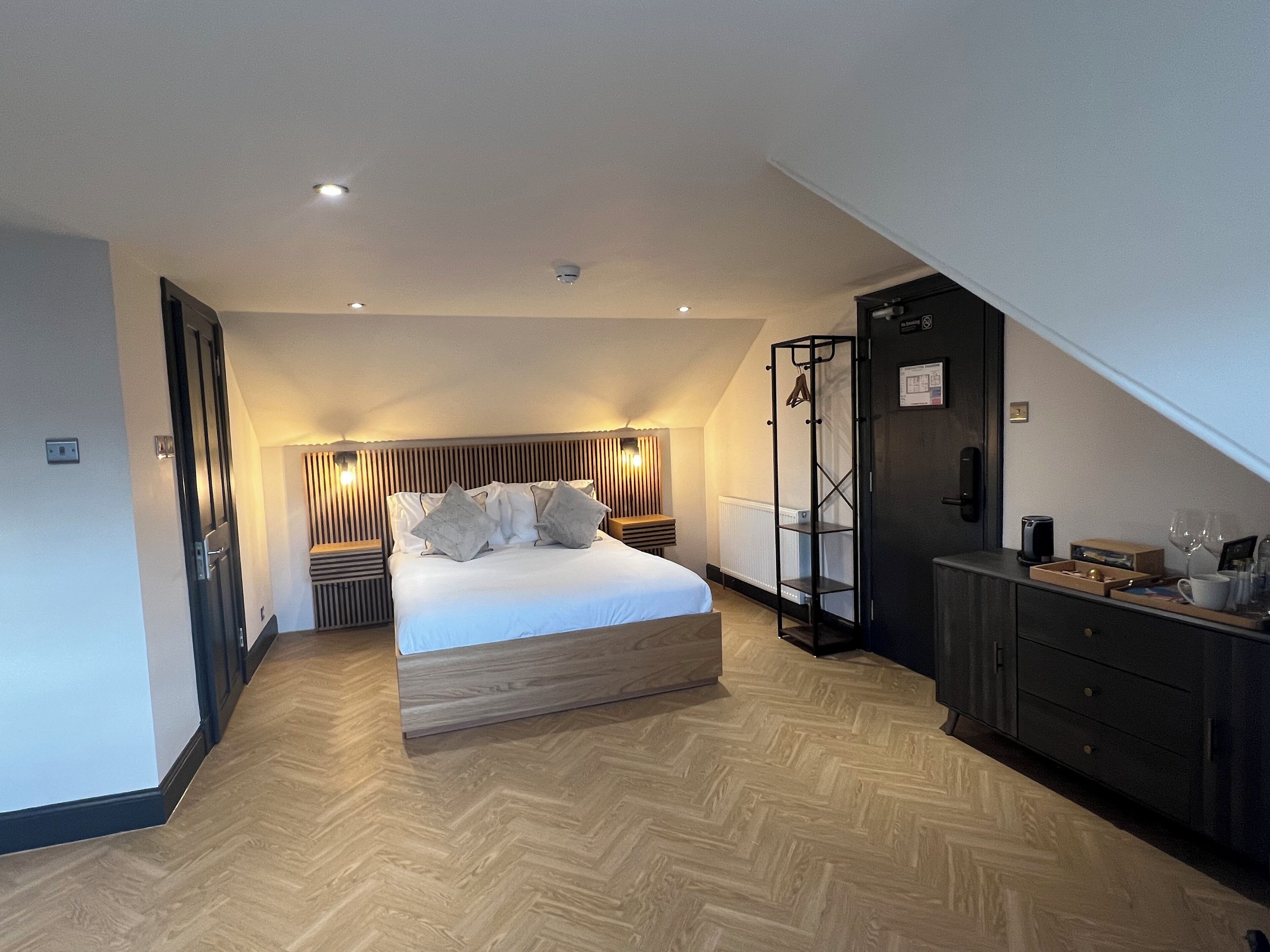 A modern bedroom with a wooden bed, a black wardrobe, and a wooden floor.