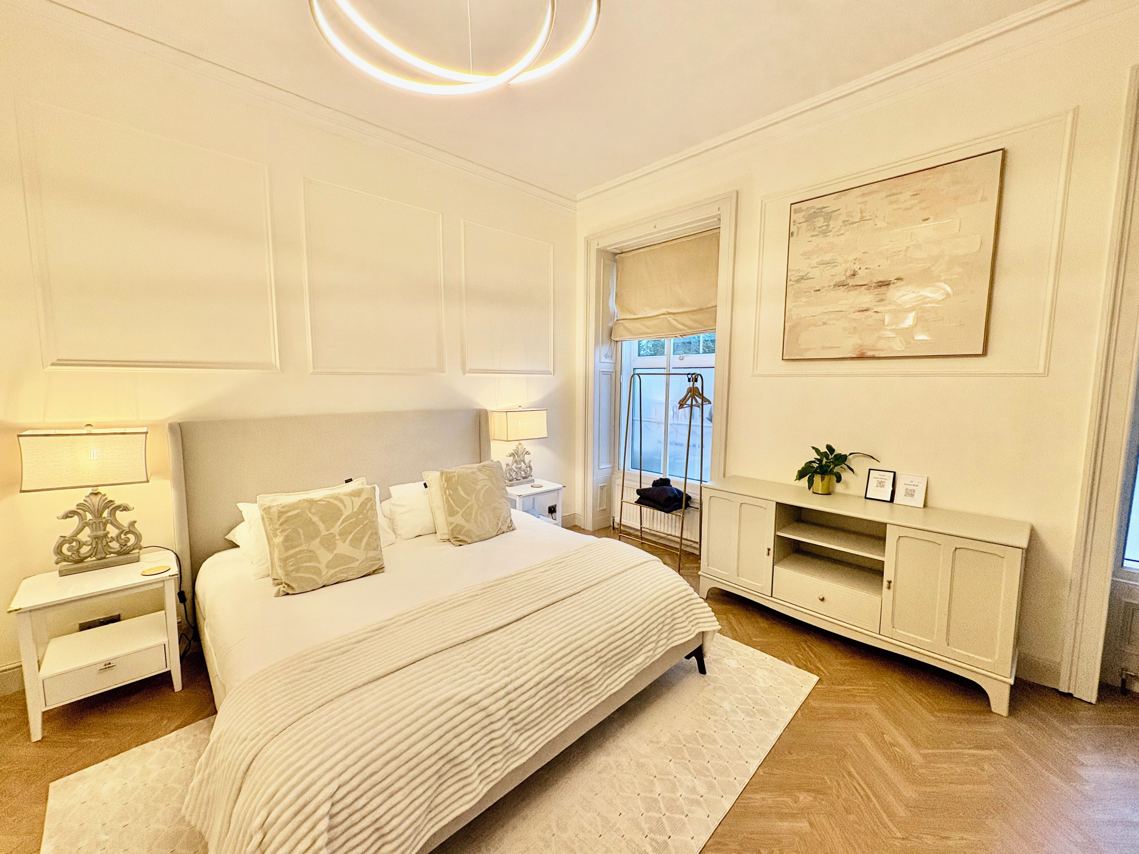 A bedroom with a large bed, bedside tables, a dresser, and a mirror.