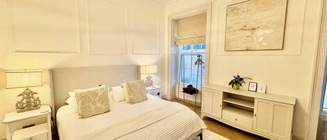 A bedroom with a large bed, bedside tables, a dresser, and a mirror.