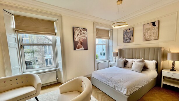 A bedroom with a large bed, a chair, a nightstand, and artwork on the walls. - ApartNest Auchterarder (Auchterarder)