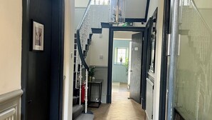 A hallway with a wooden herringbone floor, a black door on the left, and a staircase leading to an upper level. - ApartNest Auchterarder (Auchterarder)