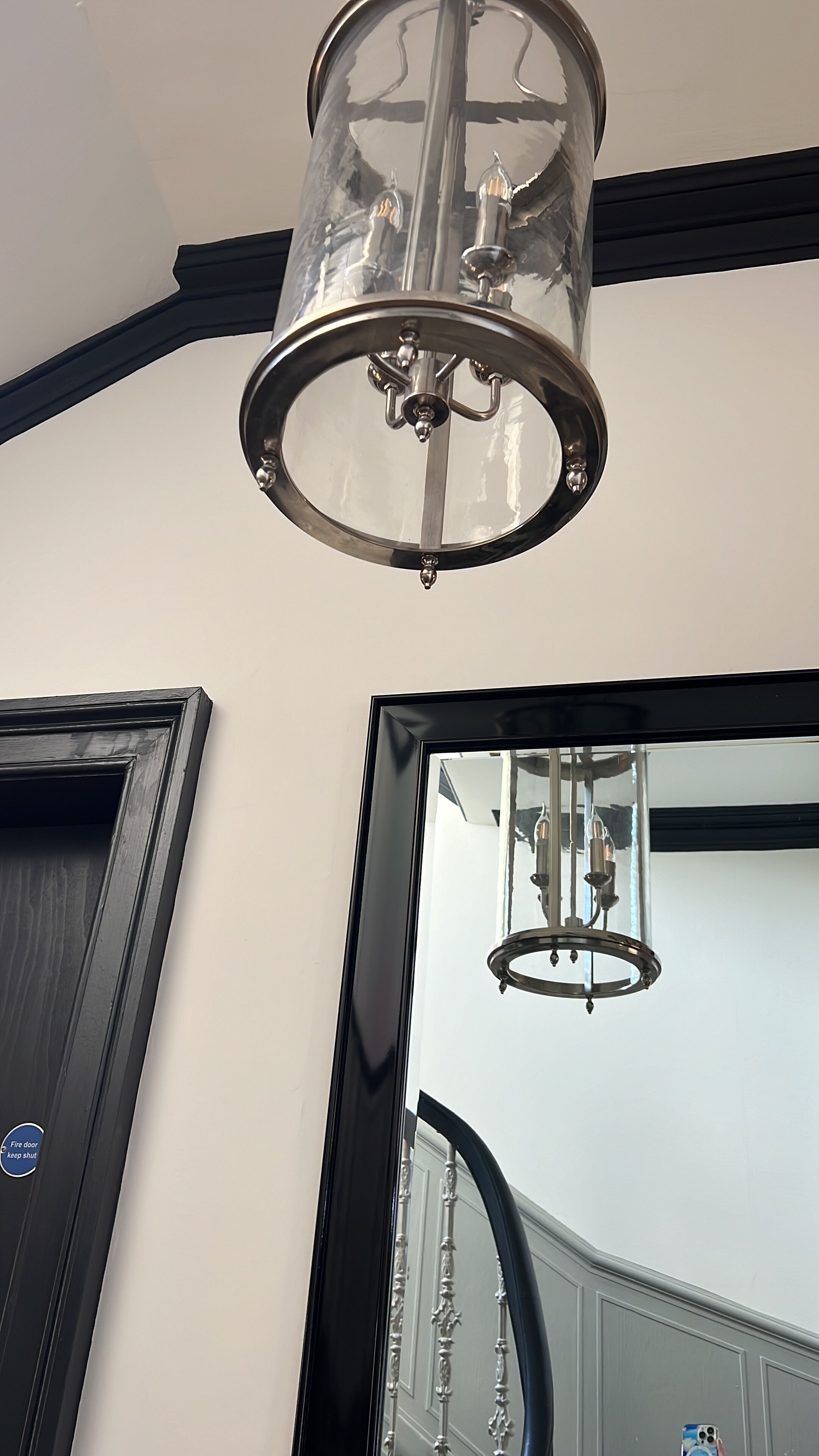 Un interior moderno con una gran lámpara de cristal y una puerta con marco negro.
