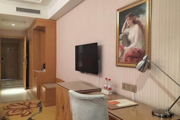 A hotel room with a desk, a television, a painting on the wall, and a lamp. - Vienna Hotel ( Liaocheng Tita Jinding Shopping Center Branch) (Liaocheng)