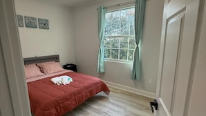 A bedroom with a bed, a window with curtains, a ceiling light fixture, and a door. - Apartment B in a two-story duplex. (Tampa)