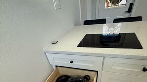 A kitchen with a white countertop, a black induction cooktop, and a drawer with four pots. - Apartment B in a two-story duplex. (Tampa)