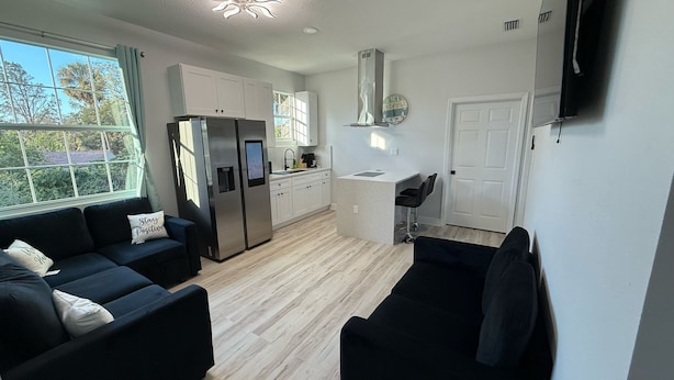 A modern kitchen with white cabinets, a built-in refrigerator, and a small island with bar stools. - Apartment B in a two-story duplex. (Tampa)