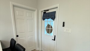 A hallway with a white door, a window with a dark valance, and a black chair. - Apartment B in a two-story duplex. (Tampa)