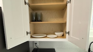 A kitchen with a microwave, a blue towel, and a shelf with plates and cups. - Apartment B in a two-story duplex. (Tampa)